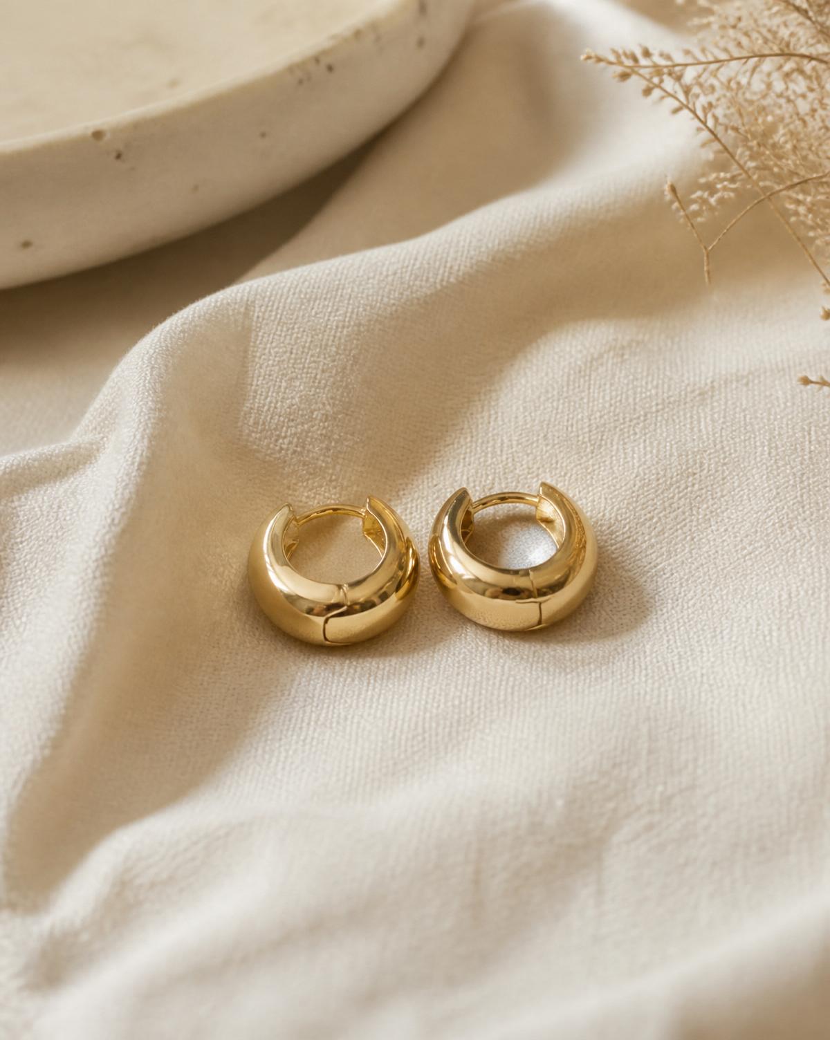 Camille chunky gold huggie hoop earrings on cream linen