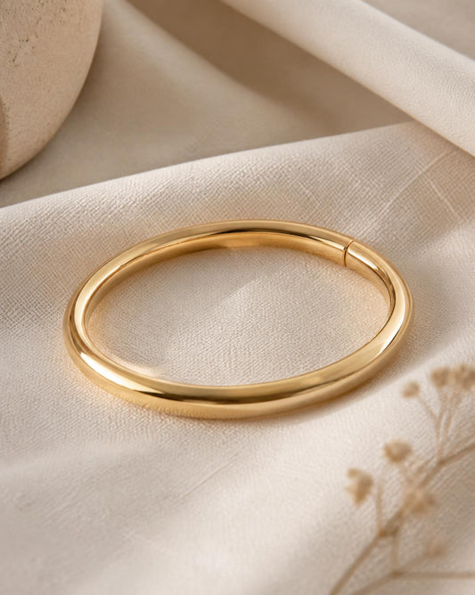 Solène polished gold bangle on cream linen