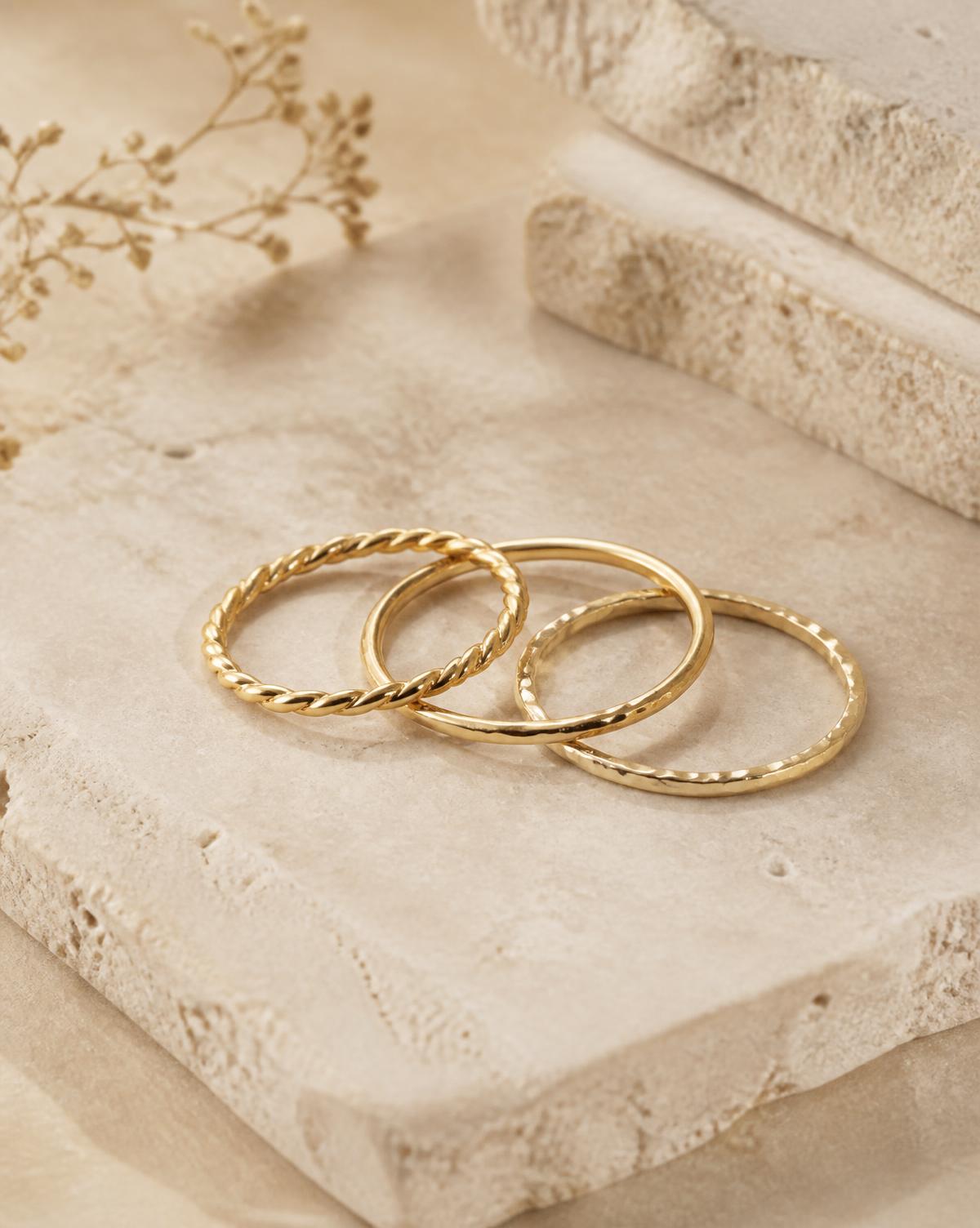 Trio of fine gold stacking rings on travertine stone