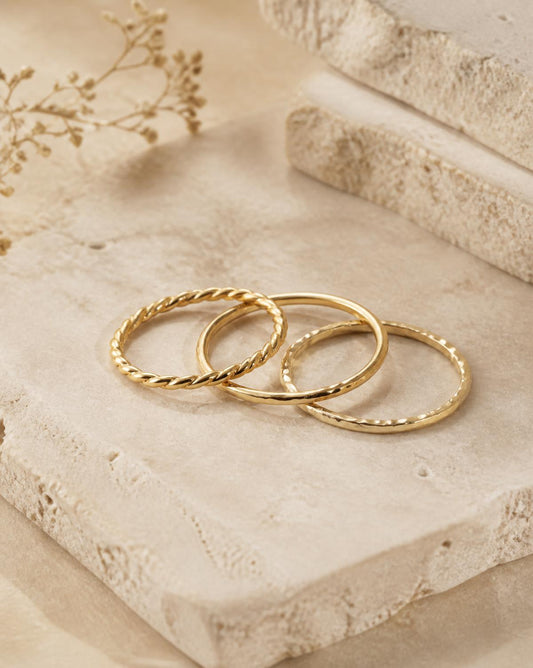 Trio of fine gold stacking rings on travertine stone